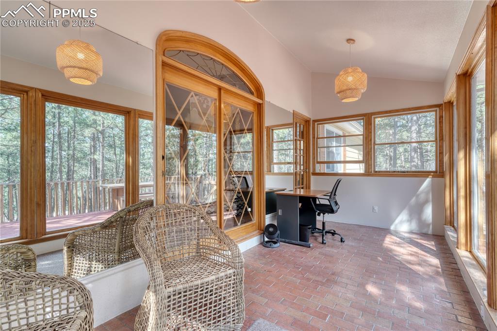 Image 11 of 50: Sunroom with brick floors and lofted ceiling