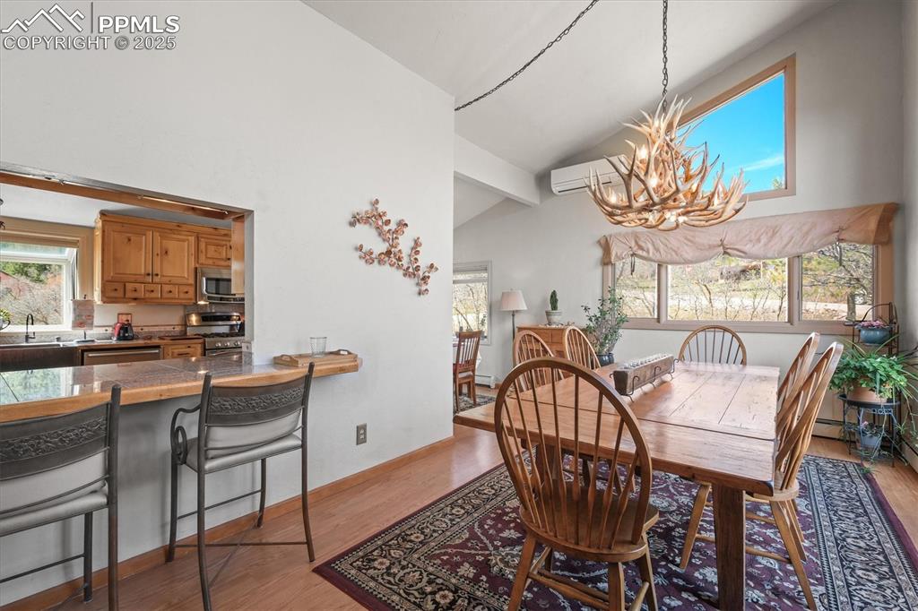 Image 11 of 49: Dining space featuring light wood-style floors, high vaulted ceiling, a cha
