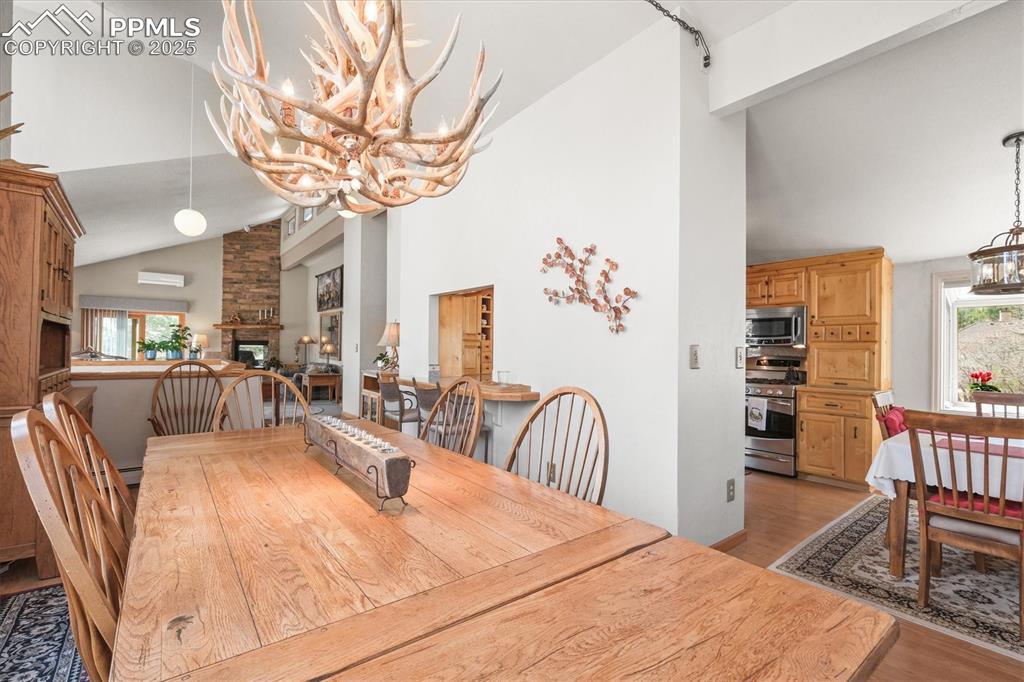 Image 12 of 49: Dining area featuring light wood-style flooring, a chandelier, high vaulted