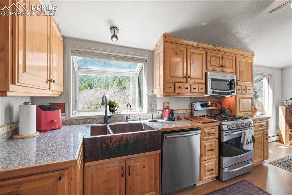 Image 17 of 49: Kitchen with tile countertops, a wealth of natural light, appliances with s