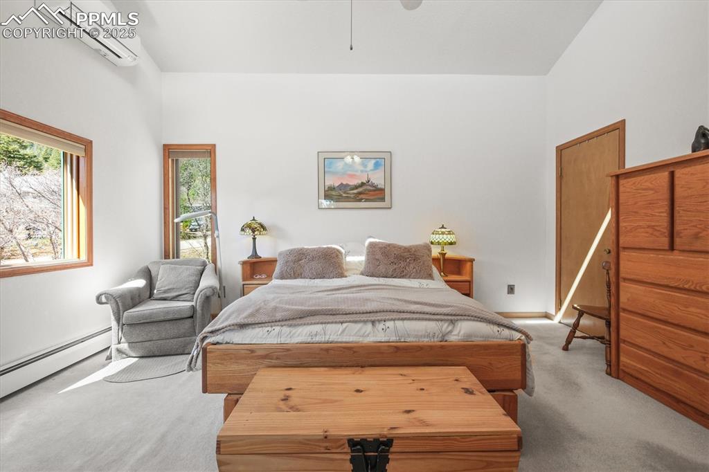 Image 26 of 49: Carpeted bedroom with baseboards, an AC wall unit, and a baseboard radiator