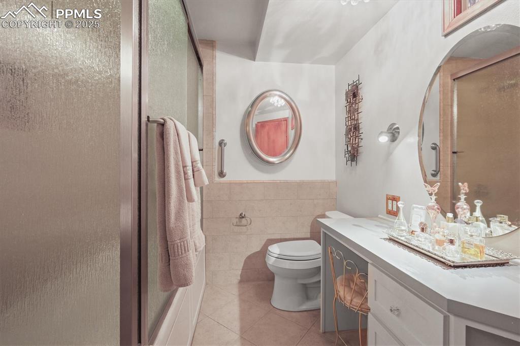 Image 35 of 49: Lower level bathroom featuring tile patterned floors, tile walls, a shower