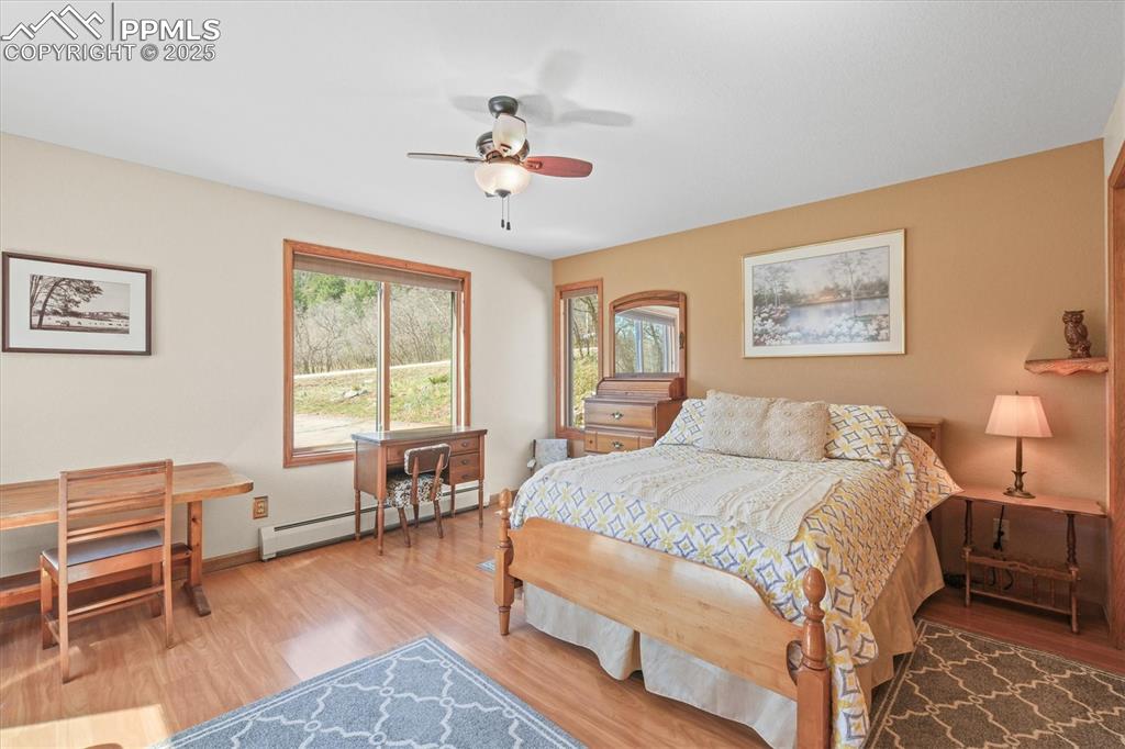 Image 40 of 49: Bedroom with a baseboard heating unit, baseboards, a ceiling fan, and wood