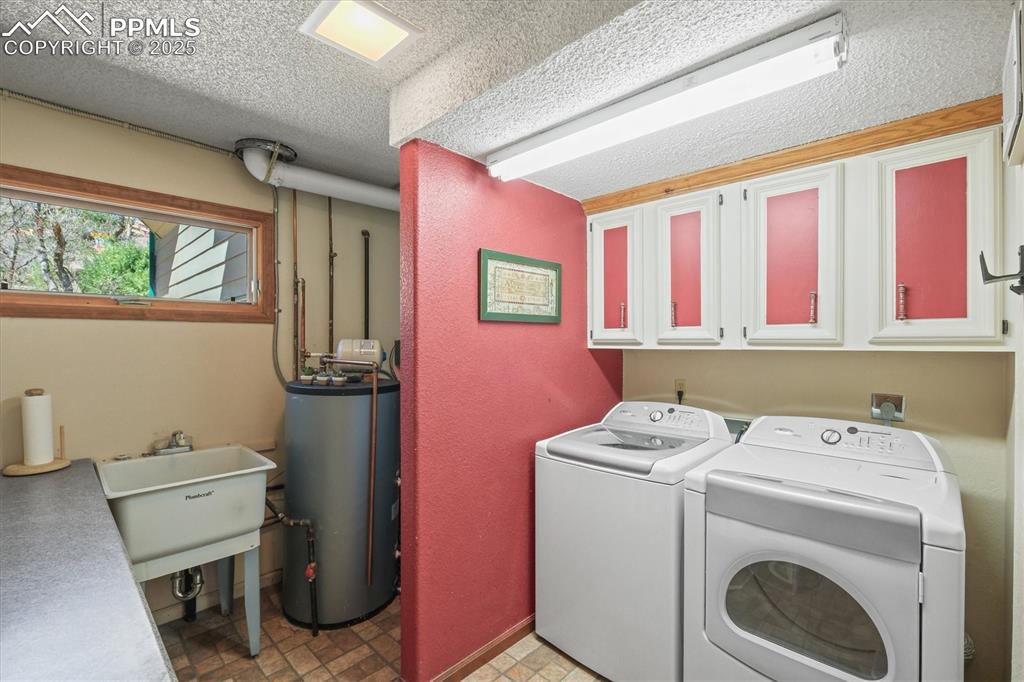 Image 42 of 49: Laundry area and utility room with a sink, water heater, cabinet space, and