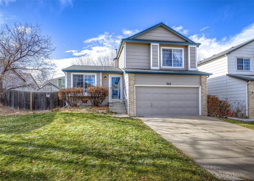 Caption: Traditional-style home featuring a garage, brick siding, and driveway