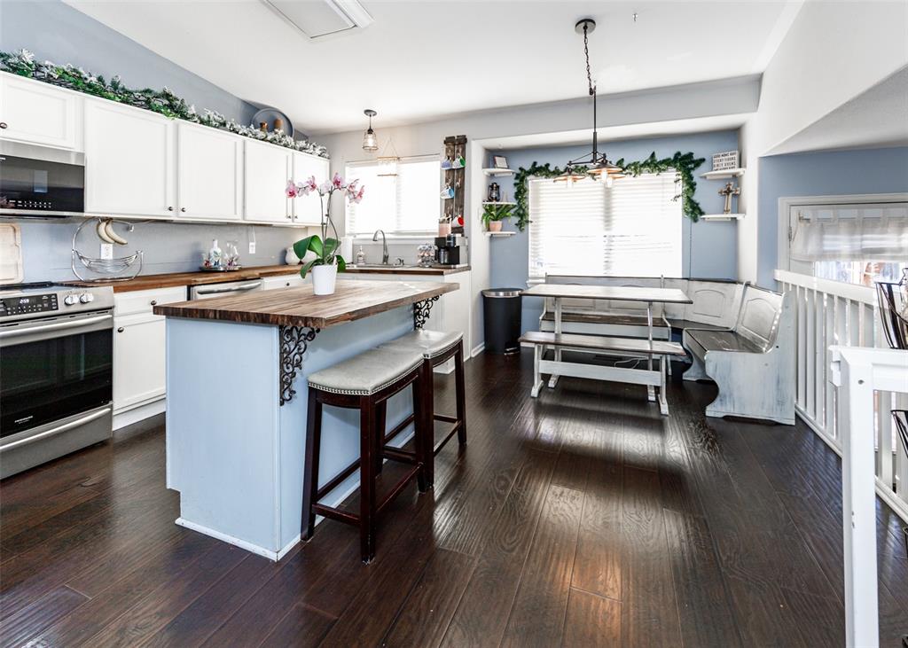 Image 13 of 42: Kitchen featuring white cabinetry, wood counters, decorative light fixtures