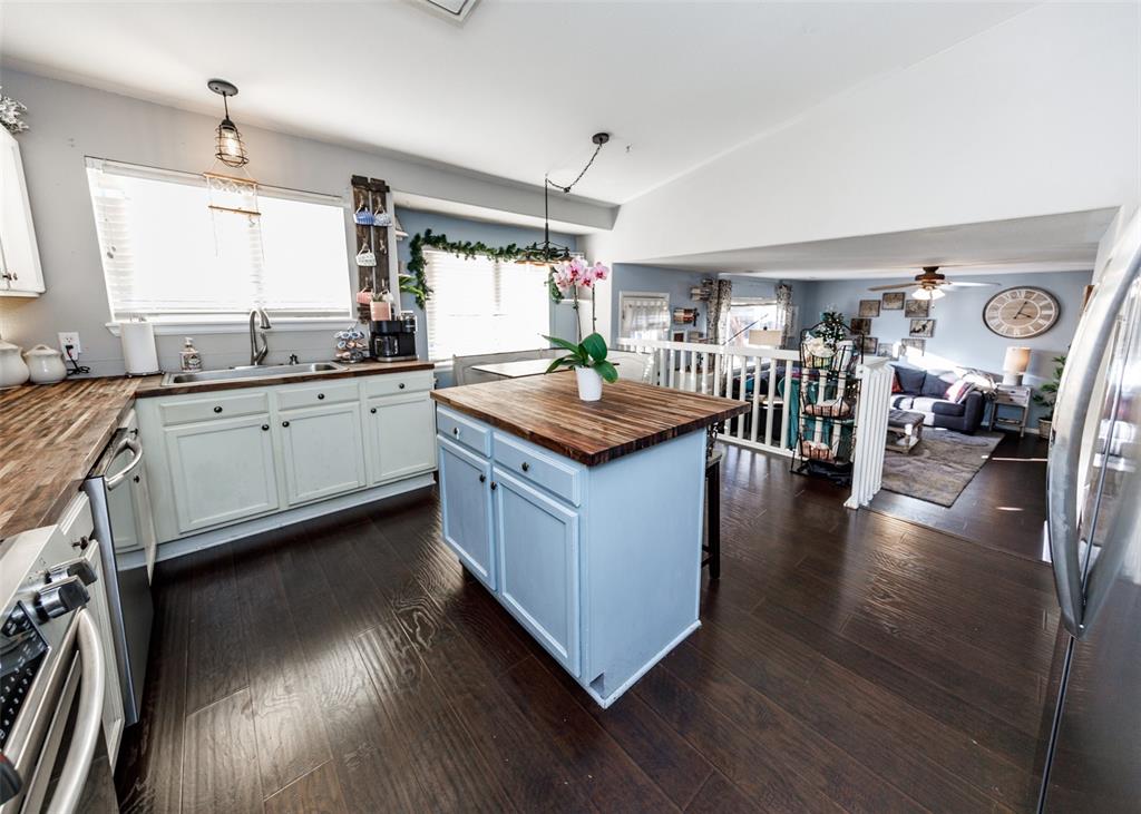 Image 15 of 42: Kitchen with butcher block counters, a breakfast bar area, pendant lighting