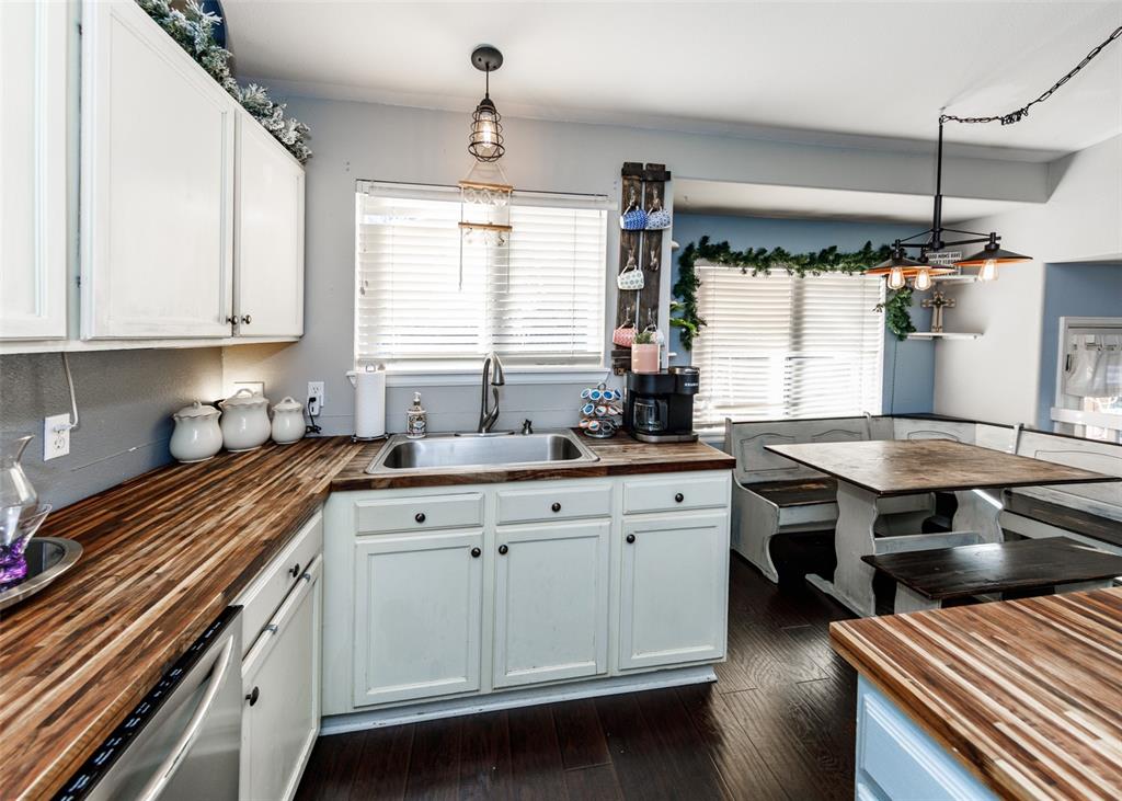 Image 16 of 42: Kitchen with wooden counters, white cabinetry, decorative light fixtures, d