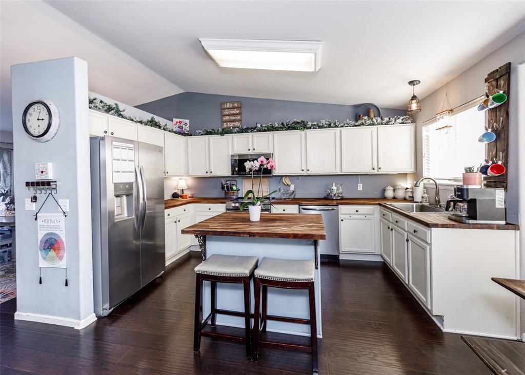 Image 18 of 42: Kitchen with stainless steel appliances, vaulted ceiling, white cabinetry,