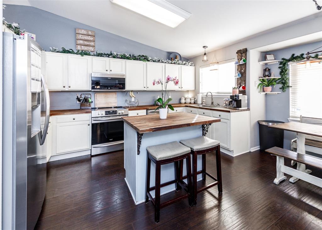 Image 19 of 42: Kitchen with butcher block countertops, stainless steel appliances, white c