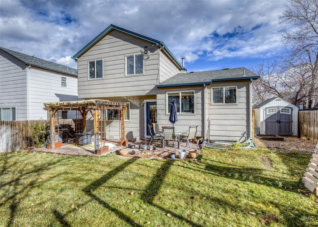 Image 2 of 42: Back of house with a storage shed, a patio area, a pergola, and roof with s