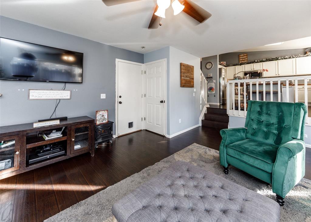 Image 26 of 42: Living room with dark wood-style floors, ceiling fan, and stairway