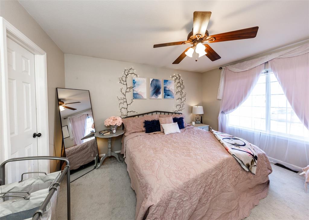 Image 33 of 42: Carpeted bedroom featuring multiple windows and ceiling fan