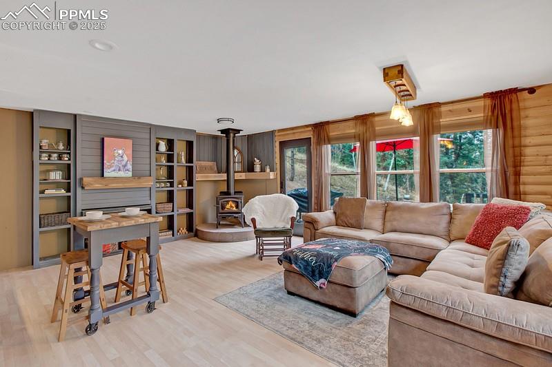 Image 16 of 27: Living area with a wood stove and light wood-type flooring