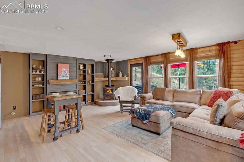 Image 17 of 27: Living area with a wood stove, plenty of natural light, and light wood-styl