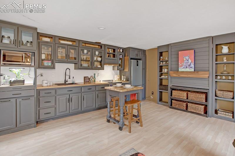 Image 18 of 27: Indoor wet bar with appliances with stainless steel finishes and light wood