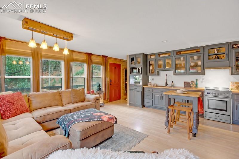 Image 19 of 27: Living area featuring bar with sink and light wood-style flooring