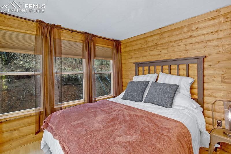 Image 22 of 27: Bedroom with rustic walls and wood finished floors