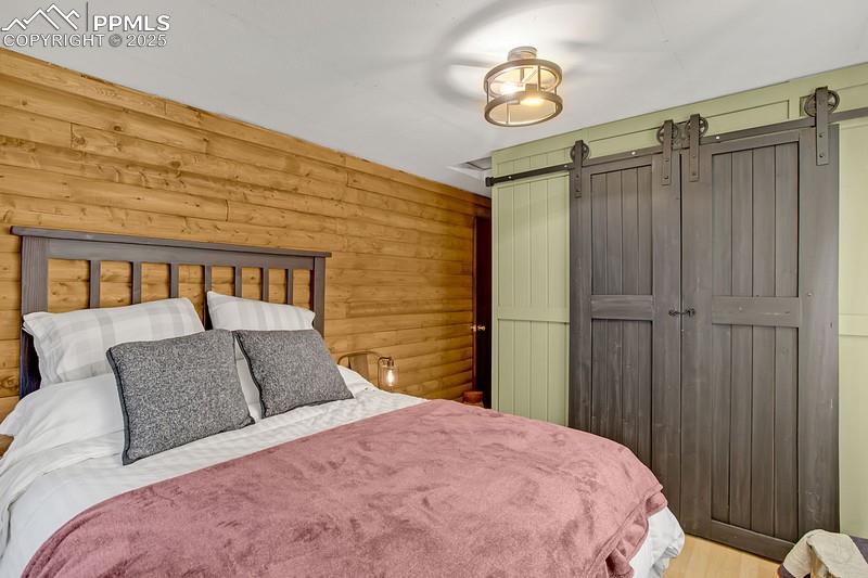 Image 23 of 27: Bedroom with a barn door, wood finished floors, and a closet