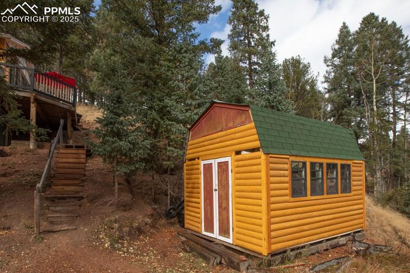 Image 25 of 27: View of shed featuring stairs and view of wooded area
