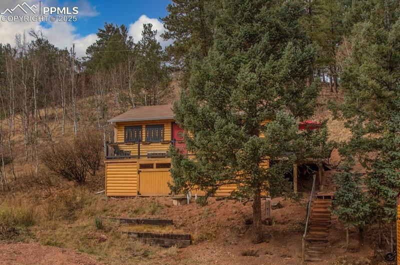 Image 3 of 27: View of front of home featuring stairway, log veneer siding, and a forest v