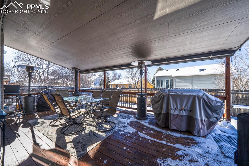 Image 30 of 38: Covered Back Deck with electric, patio table & chairs, and permanent gas li