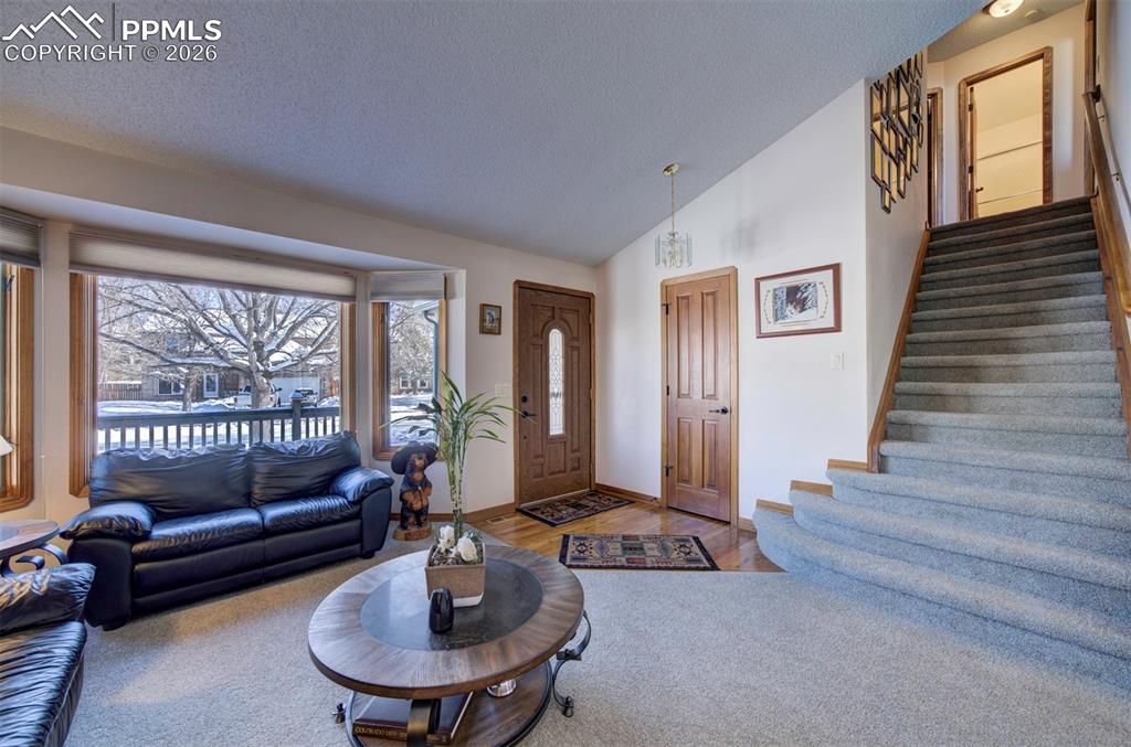 Image 7 of 38: Newly carpeted living room, natural lighting, stairs to upper level and coa