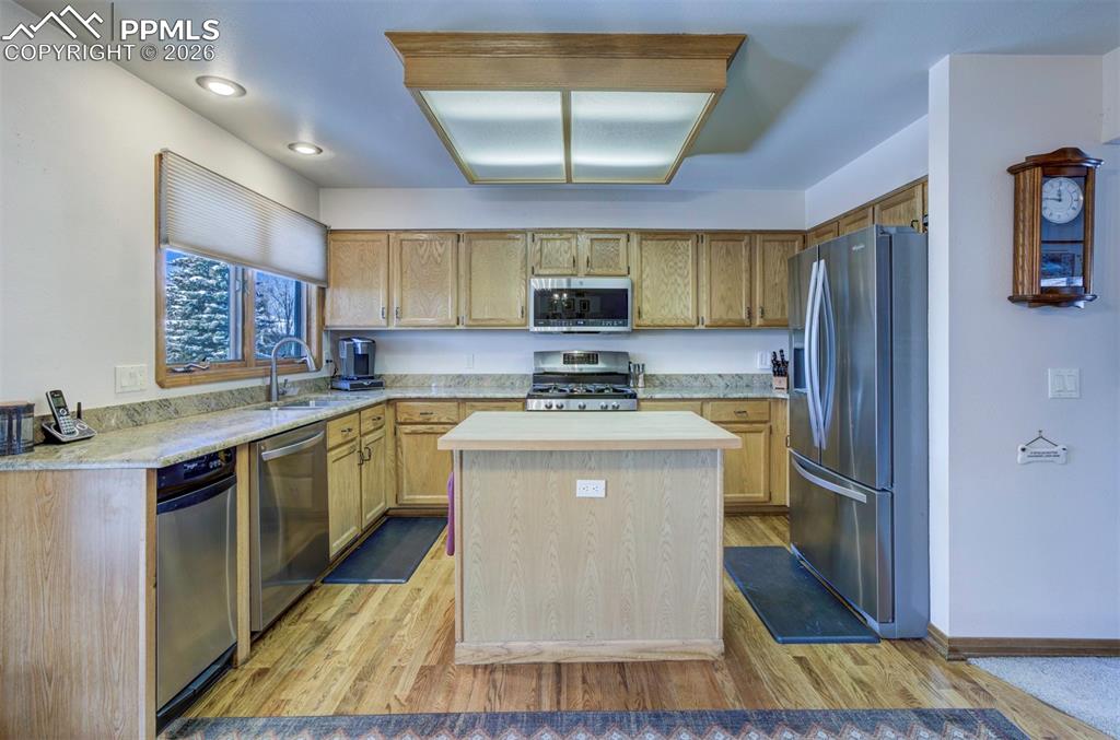 Image 8 of 38: Granite countertops, butcher block island, wood flooring, trash compactor, 