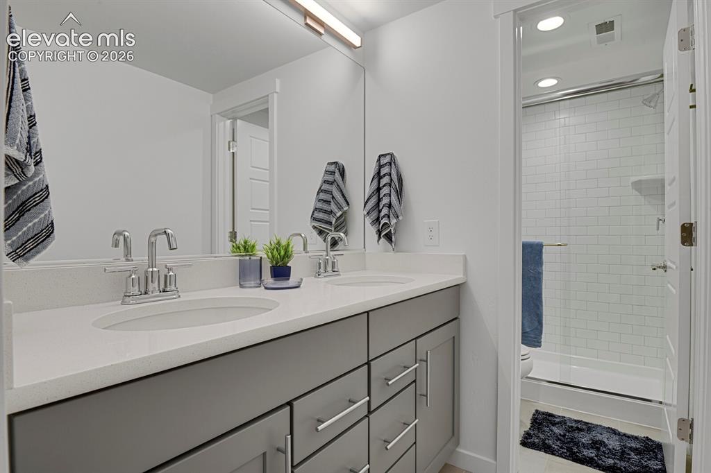 Image 36 of 44: Lower level bathroom with double sinks and closed off area for the toilet a