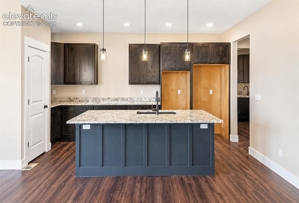 Image 11 of 40: Central kitchen island with a light-toned countertop and dark paneling