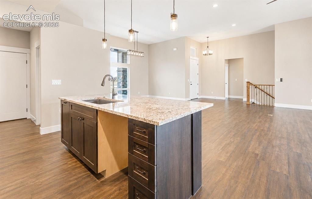 Image 13 of 40: Kitchen island with granite-style countertop, undermount sink, and dark woo