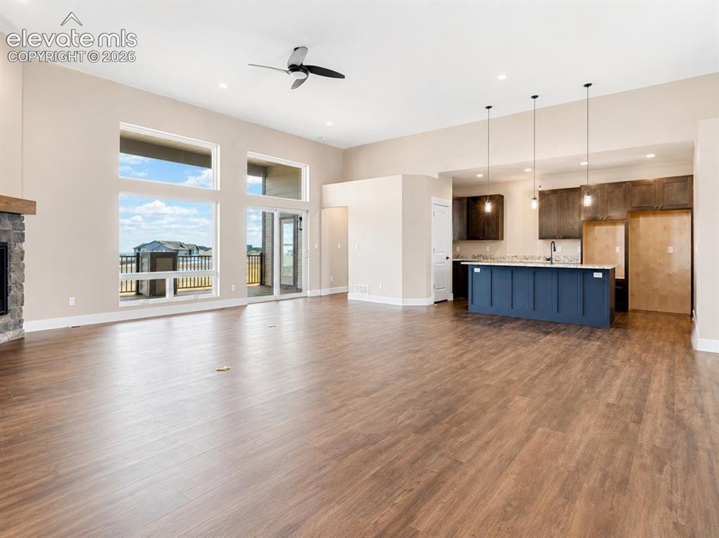 Image 17 of 40: Open-concept living area featuring wood-finish flooring, a stone-faced fire