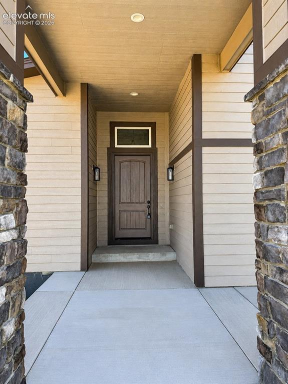 Image 3 of 40: Covered entryway featuring a paneled front door, transom window, and dual w