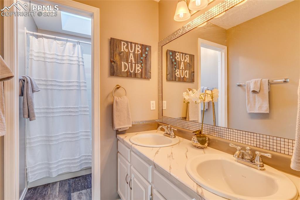 Image 12 of 31: Upper full bathroom featuring double vanity, wood finished floors, and curt