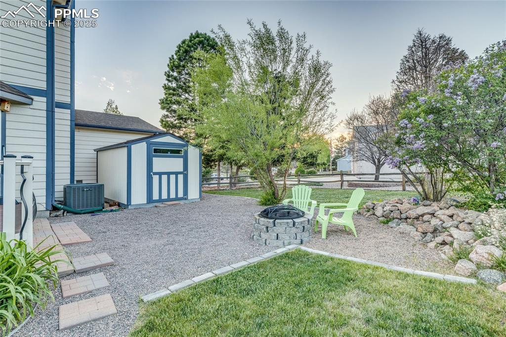 Image 24 of 31: Nicely landscaped back yard with outdoor shed with a fire pit