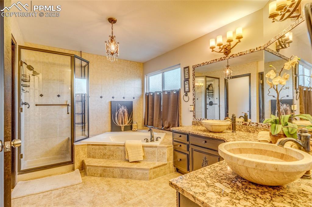 Image 8 of 31: Primary bathroom featuring vanity, a garden tub, a shower stall, and tile p