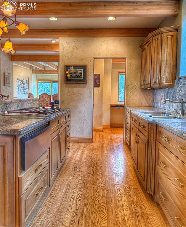 Image 6 of 20: Kitchen with stainless steel gas stovetop, a sink, light wood-style floors,