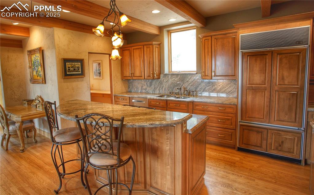 Image 7 of 20: Kitchen featuring a kitchen bar, custom cabinets, island gas cook surface w