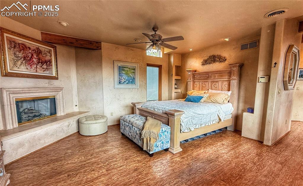 Image 8 of 20: Bedroom featuring hardwood floors, a fireplace, walk out to patio with amaz
