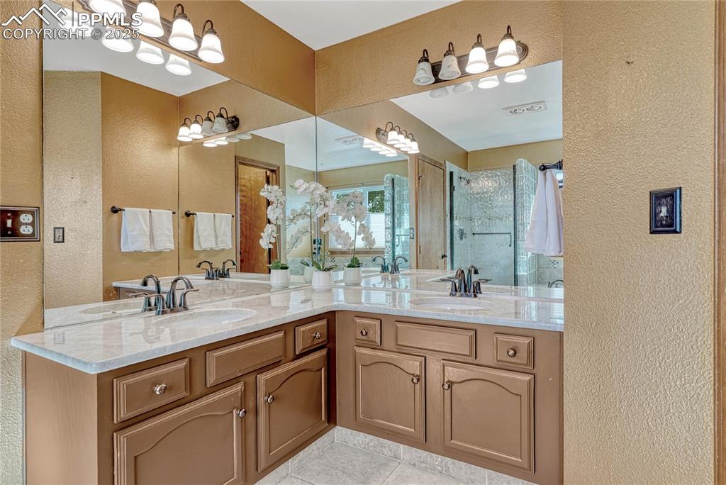 Image 10 of 48: Primary bath with tile flooring, double sinks and quartzite counters.