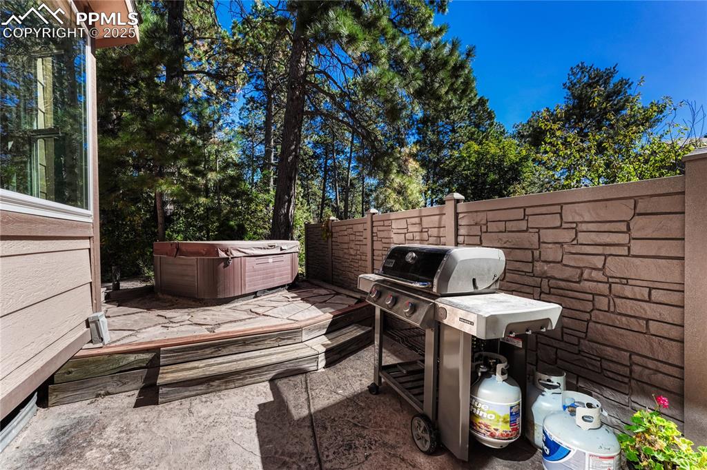 Image 17 of 48: Raised flagstone patio with hot tub and small sand area that may be used as