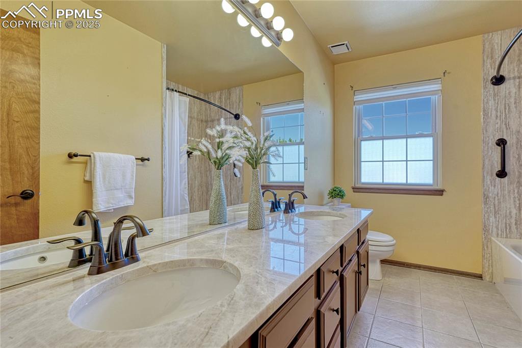 Image 32 of 48: Secondary bathroom with double sinks, tile, and quartz counter