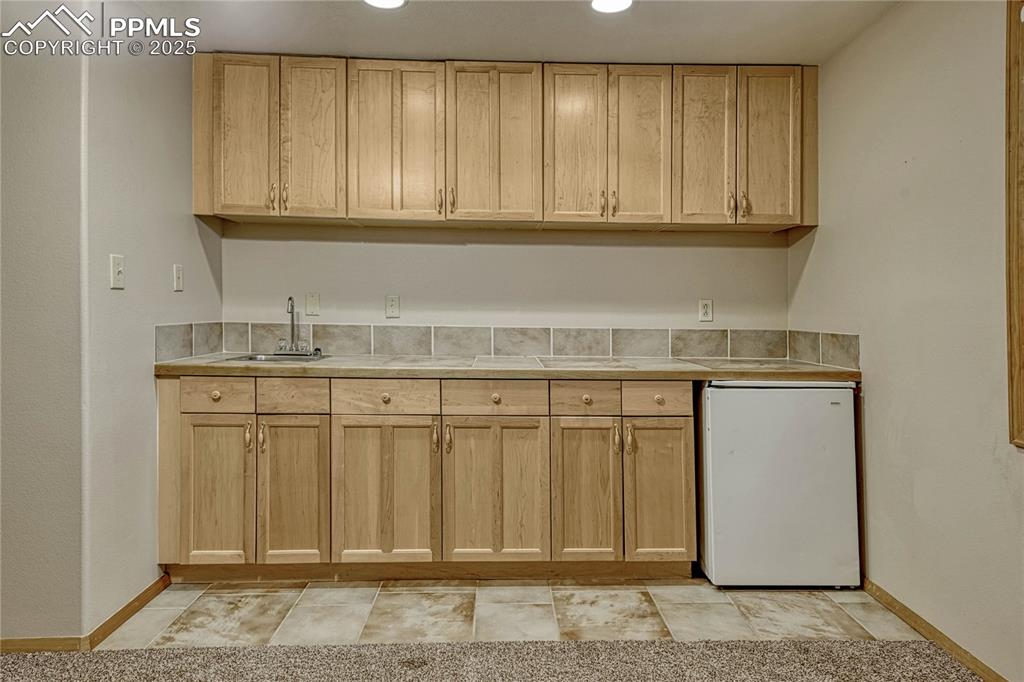 Image 39 of 48: Wet bar with mini fridge in basement