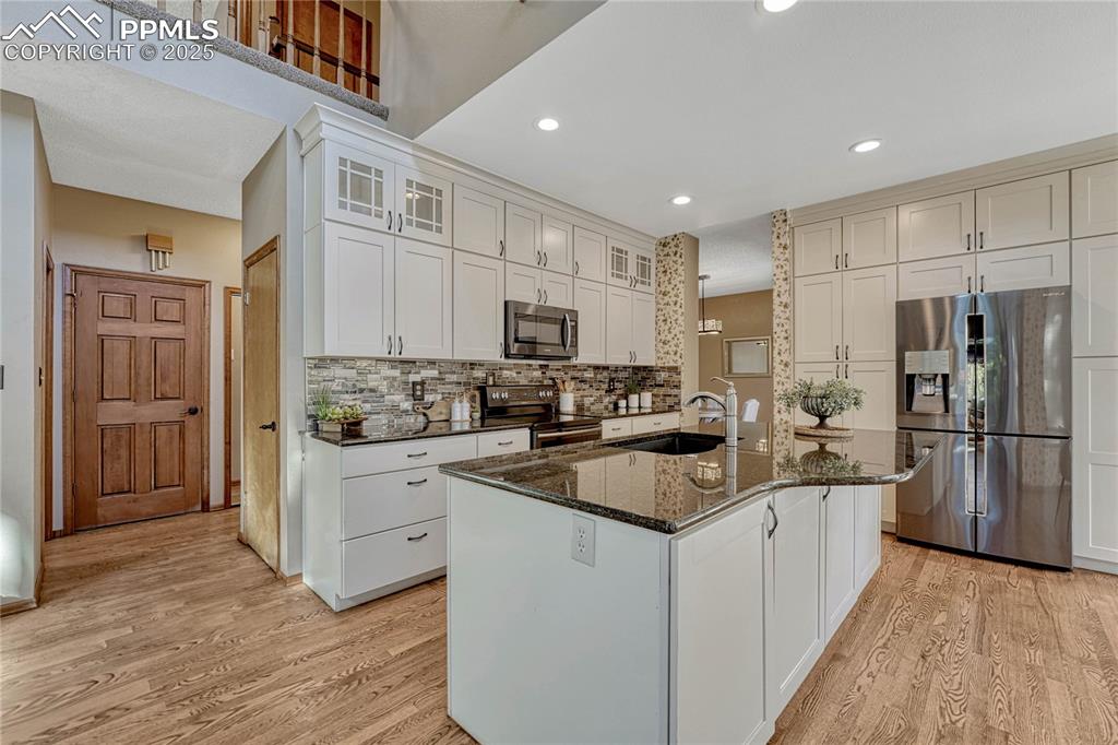 Image 5 of 48: Updated kitchen with quartz countertops, a tile backsplash, black stainless
