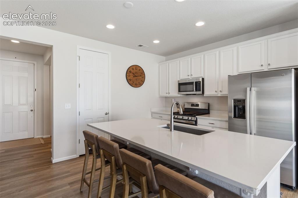 Image 12 of 33: Modern kitchen featuring a large central island with seating, white shaker-