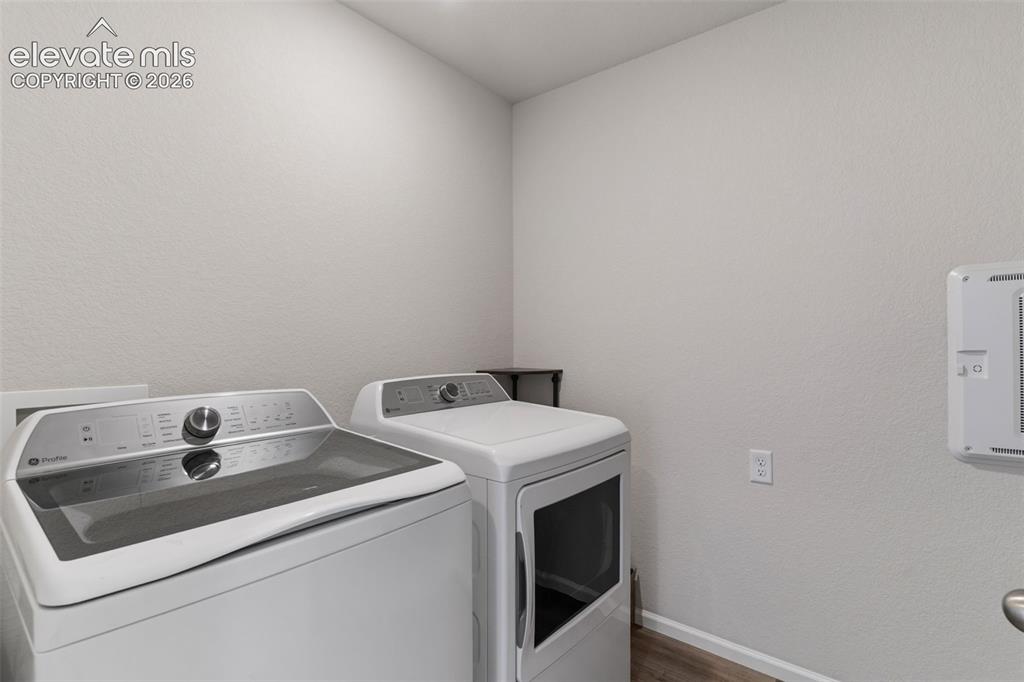 Image 17 of 33: Dedicated laundry area featuring light-toned walls, wood-finish flooring, a