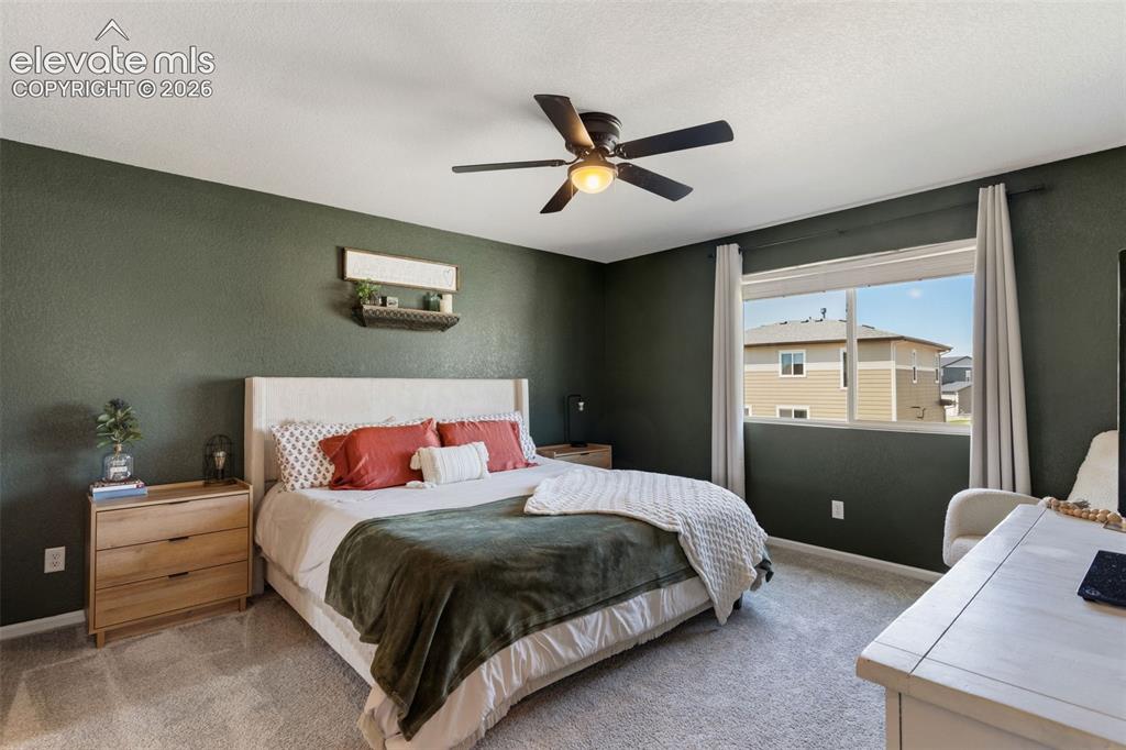 Image 18 of 33: Bedroom featuring dark green walls, a single window, and a ceiling fan with