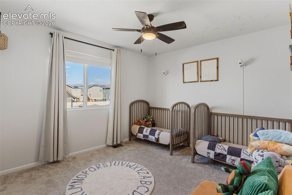 Image 27 of 33: Bright room featuring a ceiling fan, plush carpeting, and a window with whi