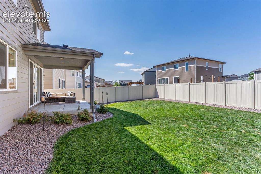 Image 29 of 33: Expansive green lawn with a covered concrete patio