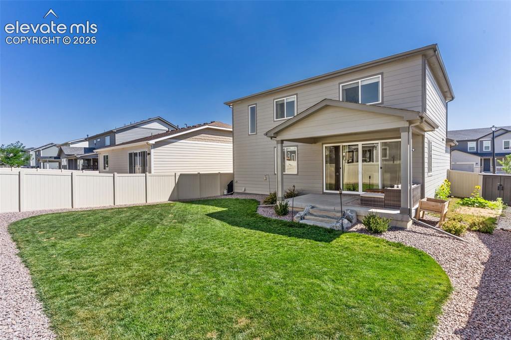 Image 30 of 33: Expansive backyard featuring a manicured lawn, a gravel pathway, and a priv
